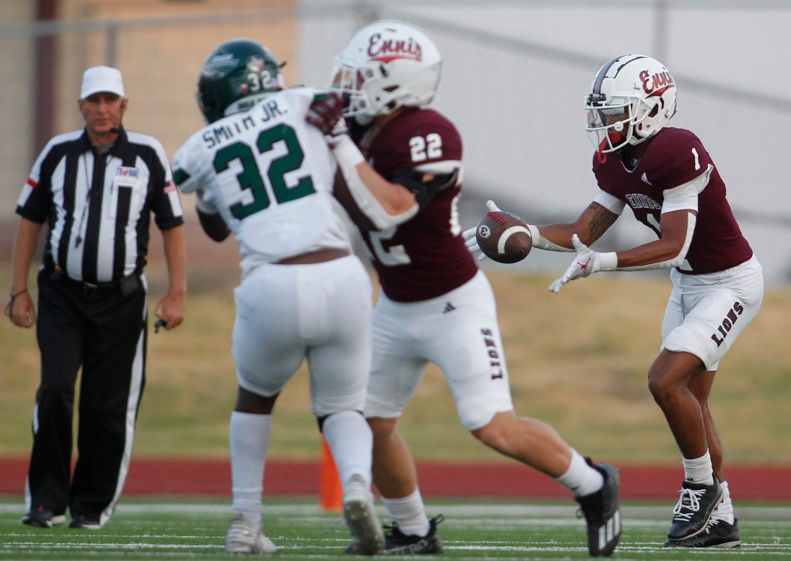 Ennis punter Gracen Harris (1) fields a snap as teammate Malachi Perez (22) blocks...