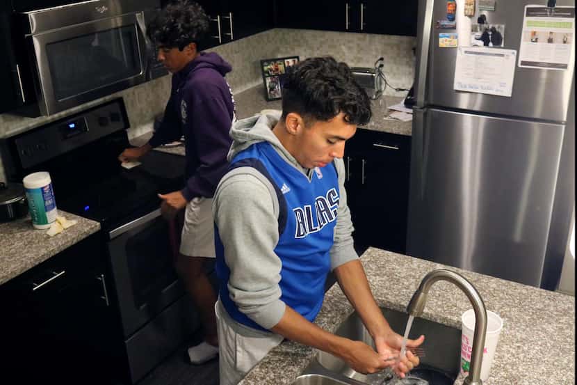 Johan Gómez lava los platos mientras su hermano menor, Jonathan, limpia la cocina en su...