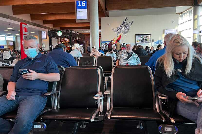 Masked and unmasked Southwest Airlines passengers sit at Gate 16 waiting to board a flight...