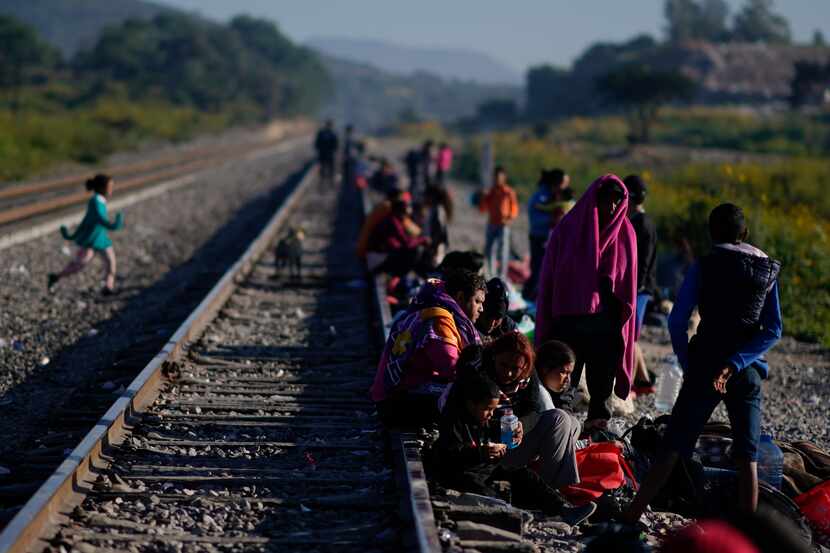Migrantes caminan a lo largo de las vías del tren con la esperanza de subirse a un tren de...
