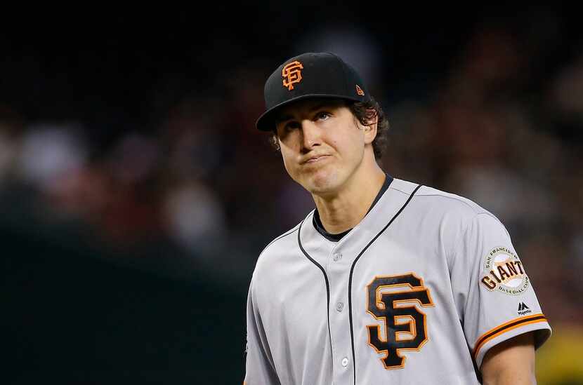 San Francisco Giants starter Derek Holland watches manager Bruce Bochy leave the dugout to...