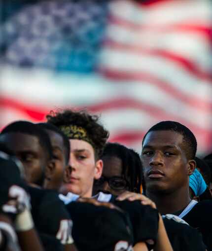 Arlington Bowie football players listen to the national anthem before a high school football...