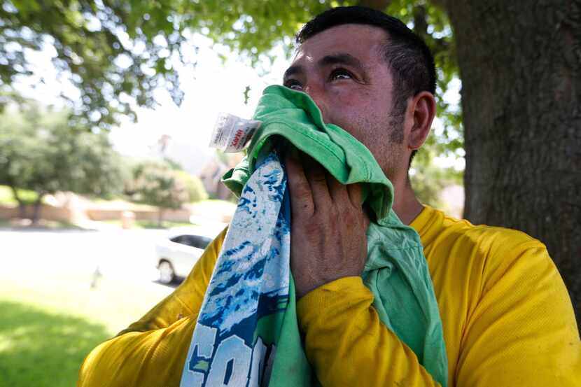 Muriel Lopez wipes his face of sweat during a break from roofing a house in Arlington, Texas...