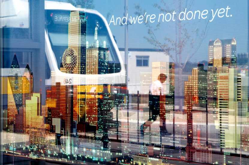 A DART train is reflected in a poster of the Dallas skyline, on display at the Irving...
