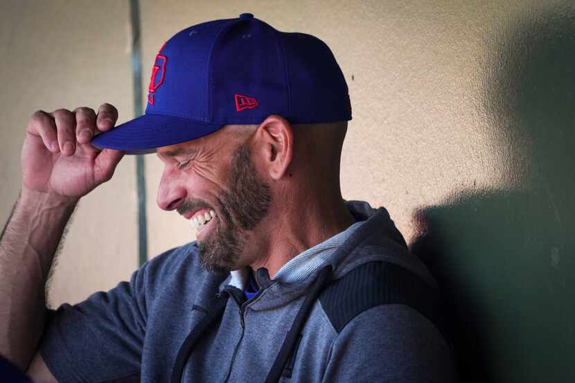 Texas Rangers manager Chris Woodward laughs in the dugout before a spring training game...