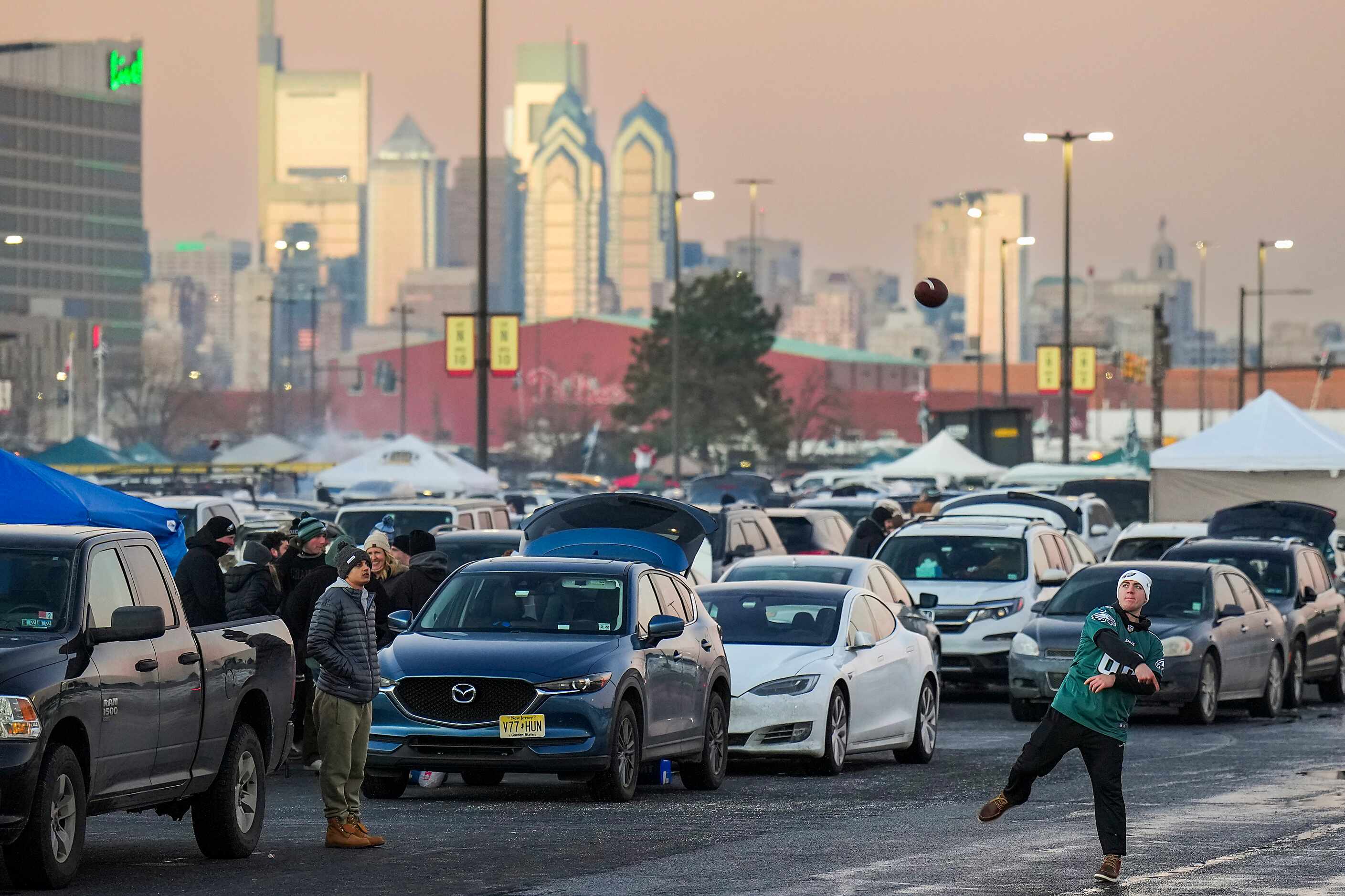 Philadelphia Eagles fans toss a football as they tailgate before an NFL football game...