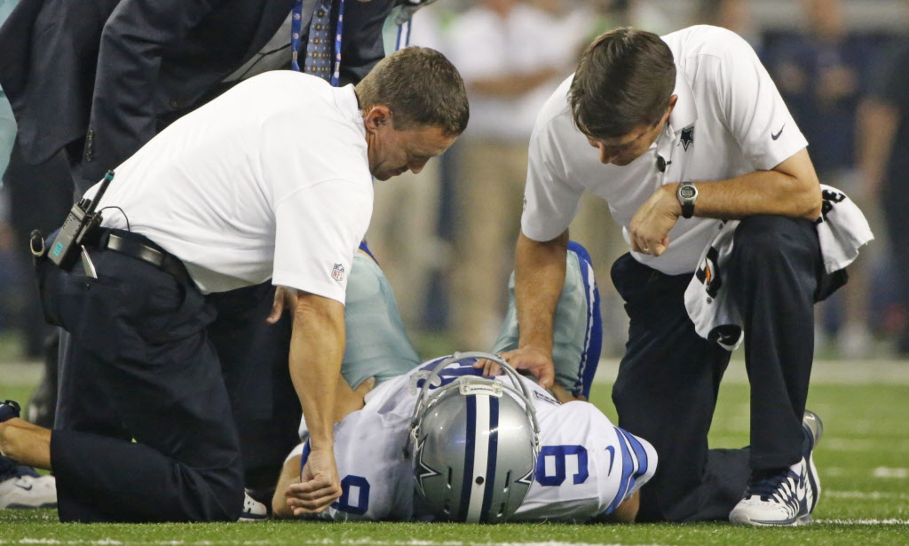 Trainers attend to Dallas Cowboys quarterback Tony Romo (9) after he was sacked by...