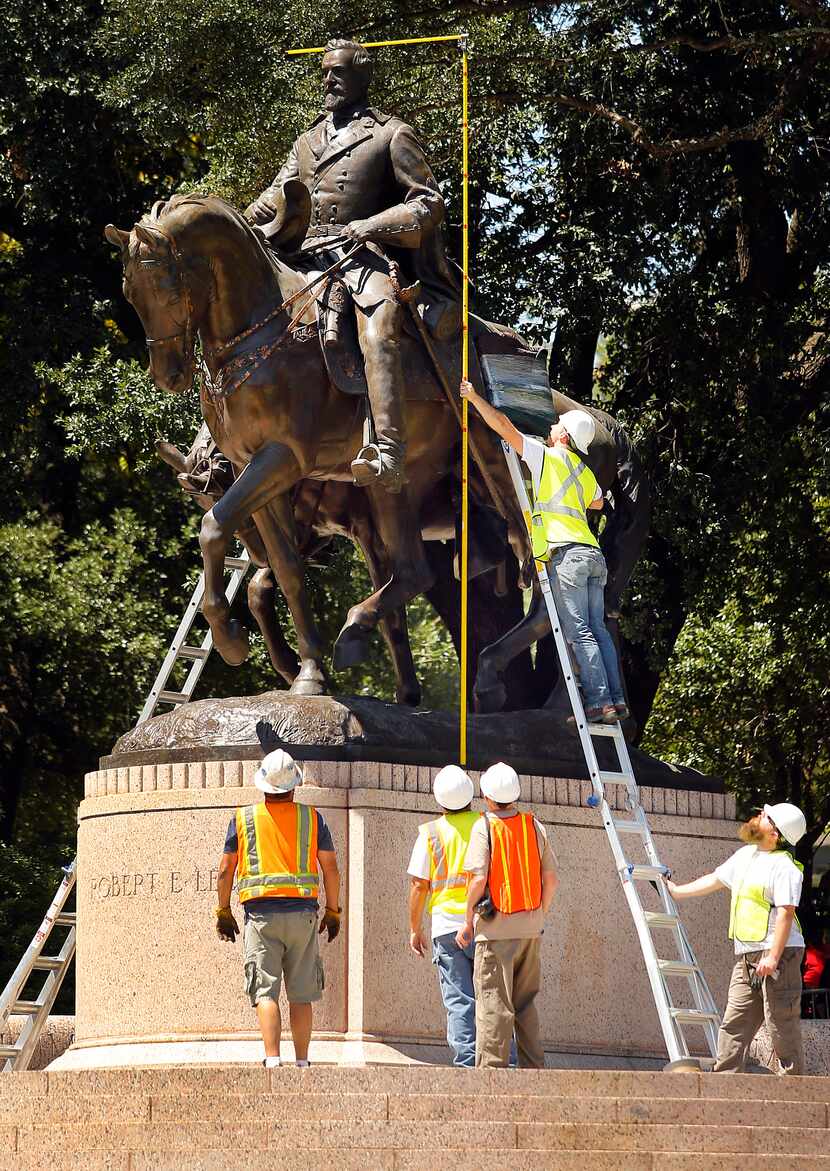 Crewmen from Howell Crane and Rigging Inc measure the height of the Robert E. Lee statue on...