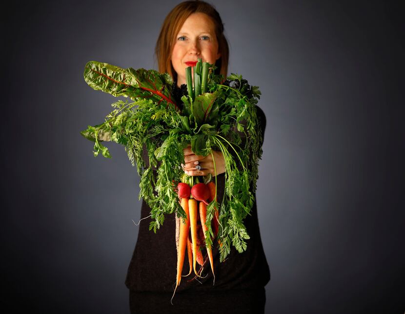 Rebecca White of A Pleasant Little Kitchen grasps a handful of vegetables she'll use to make...
