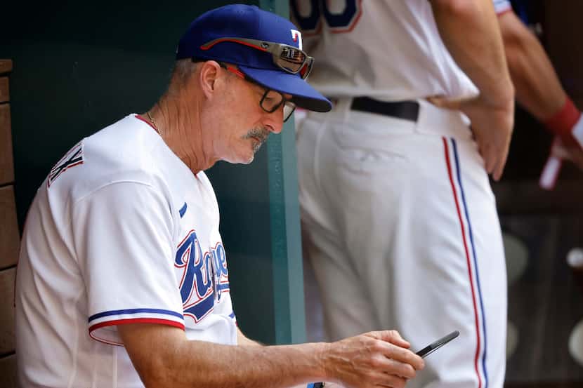 Texas Rangers pitching coach Mike Maddux looks over his tablet in the ninth inning against...