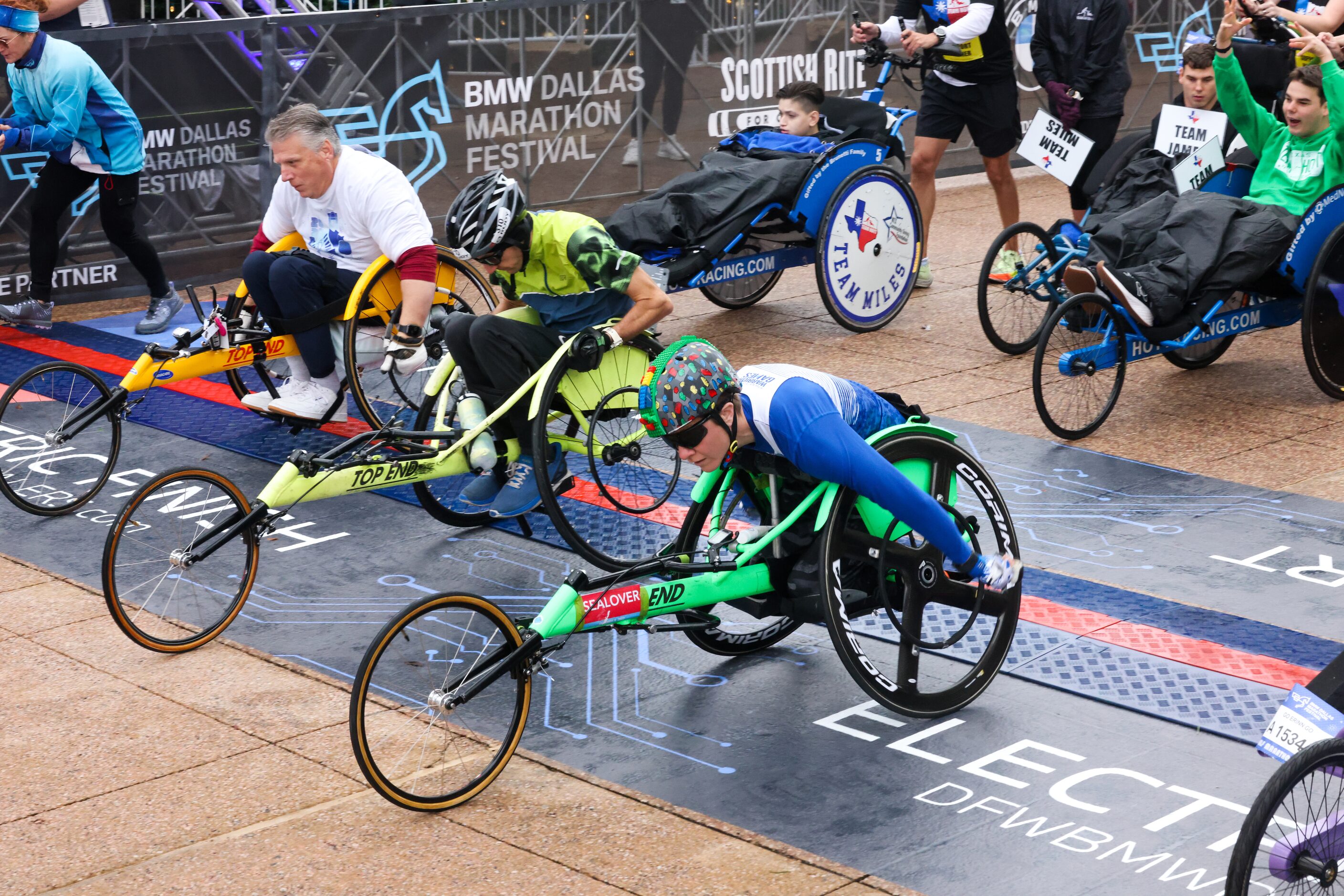 Wheelchair competitors cross the start line in front of Dallas City Hall as part of the BMW...