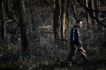  Ryan Dalby, of the Dallas Detective for Missing Persons squad, searches in the woods near...