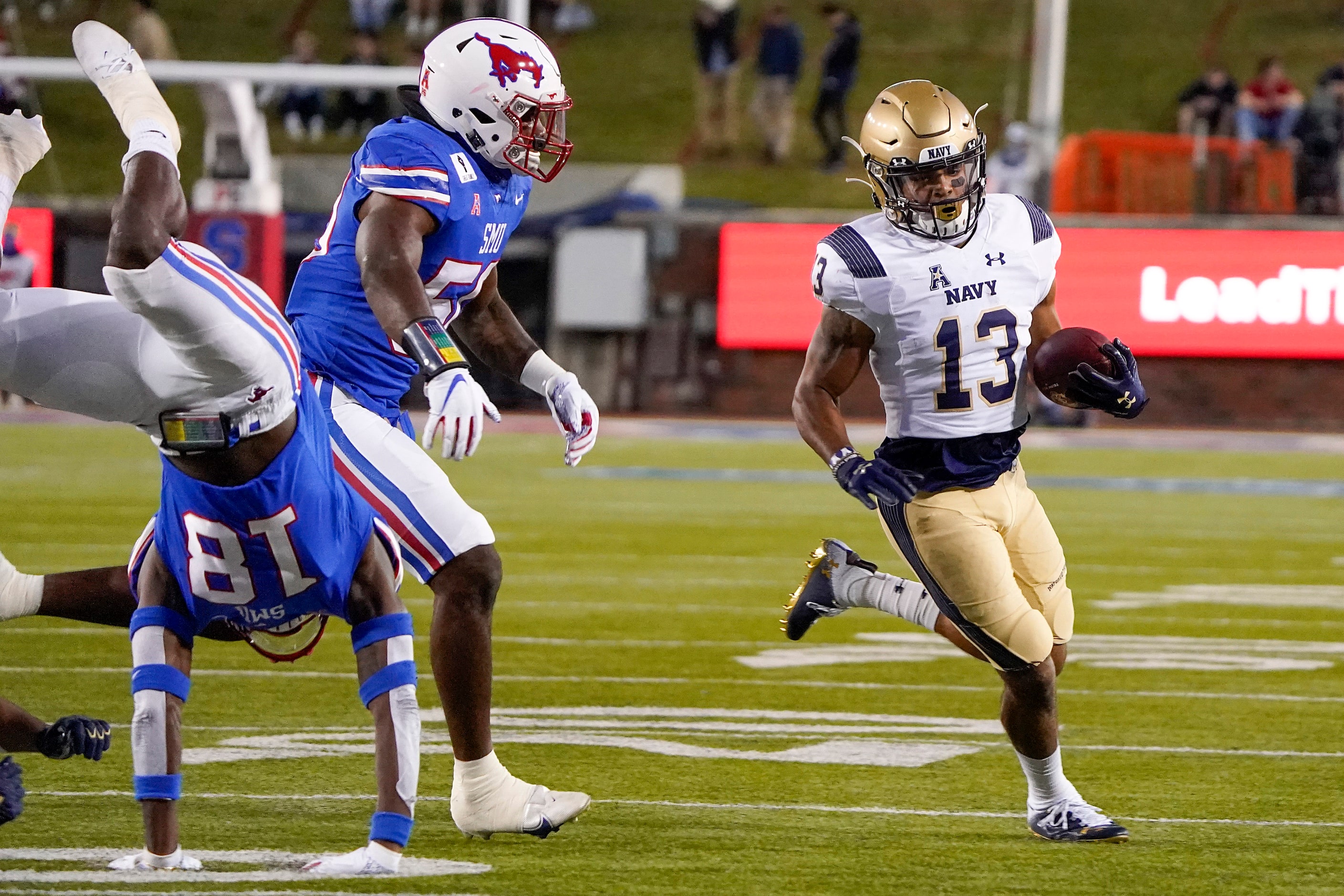 Navy running back Chance Warren (13) gets past SMU linebacker Richard McBryde (50) and...