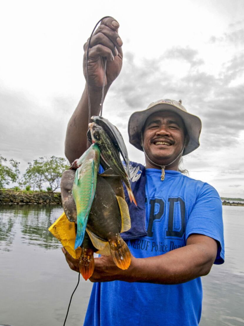 Local man holds string of fish he caught while snorkeling in Kosrae, Federated States of...