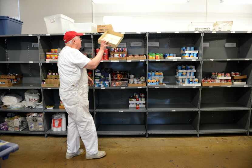 John Carpenter, a volunteer at the Irving Cares food pantry, restocks shelves in this 2013...