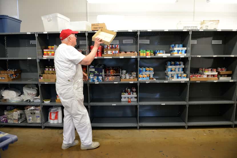John Carpenter, a volunteer at Irving Cares food pantry, restocks shelves at the end of the...