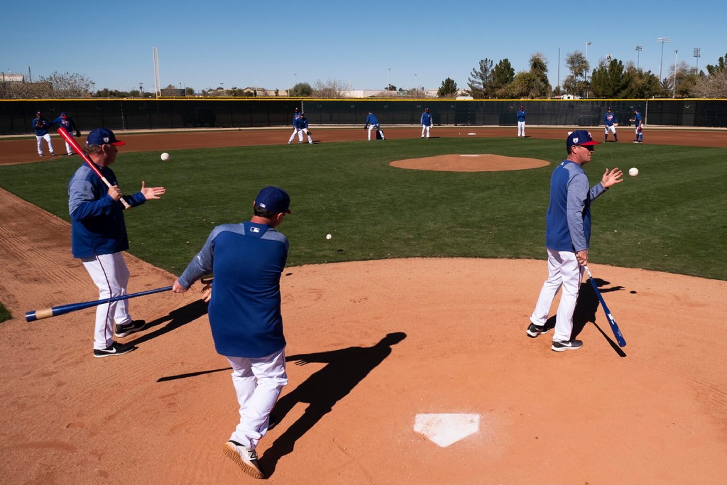 Texas Rangers coaches hit grounders for fielding practice during a spring training workout...