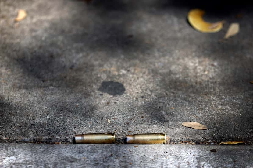 Shell casings settled in a sidewalk crease near a memorial for two shooting victims Friday...