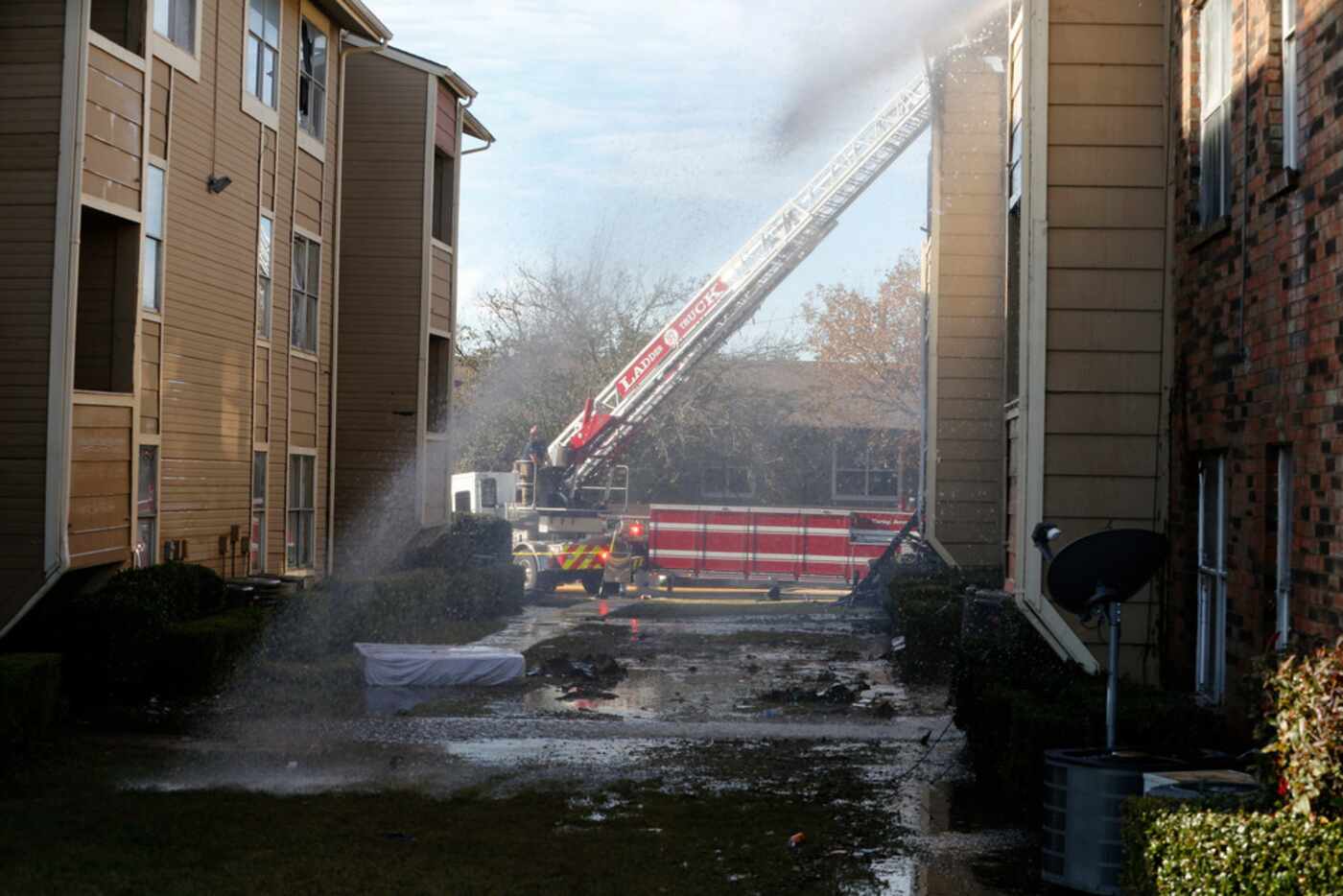 Firefighters put out hot spots on Nov. 21, 2018 during an apartment fire at the Meadows at...
