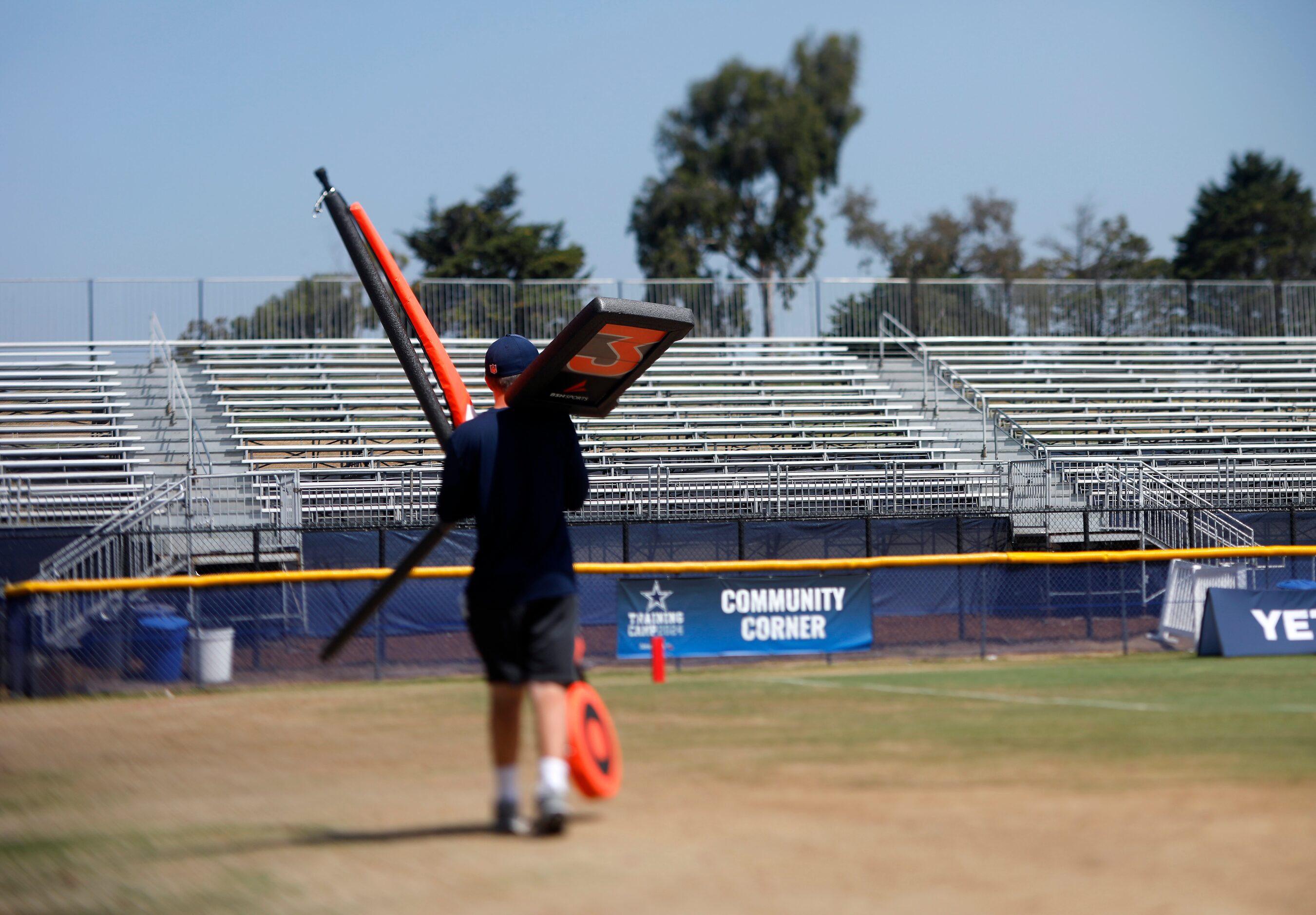 A sideline worker puts away the yardage markers following a mock game walk thru at training...