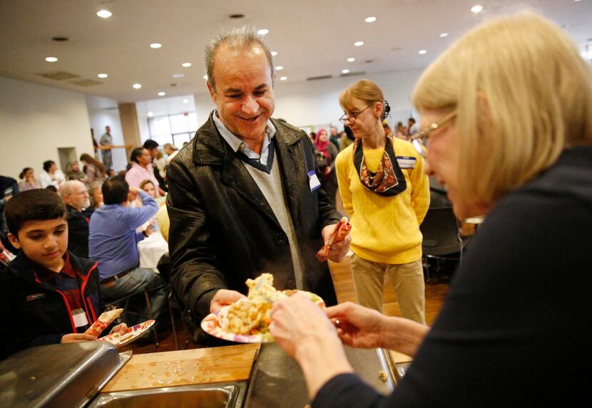 
Volunteer Suzanne Neff (right) loaded Jalal Mokhtary’s plate with macaroni and cheese...