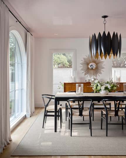 Dining room with black dining table and chairs, a rug, and a pale pink ceiling.
