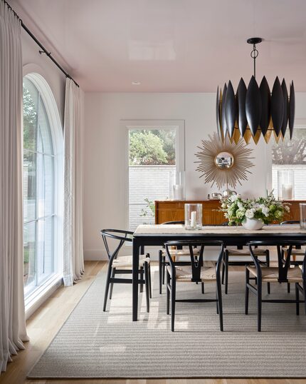 Dining room with black dining table and chairs, a rug, and a pale pink ceiling.