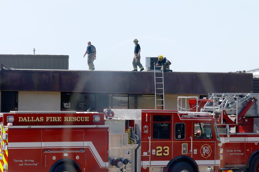 Firefighters check around the rooftop at the scene of a fire at Nolan Estes Plaza.Thursday,...