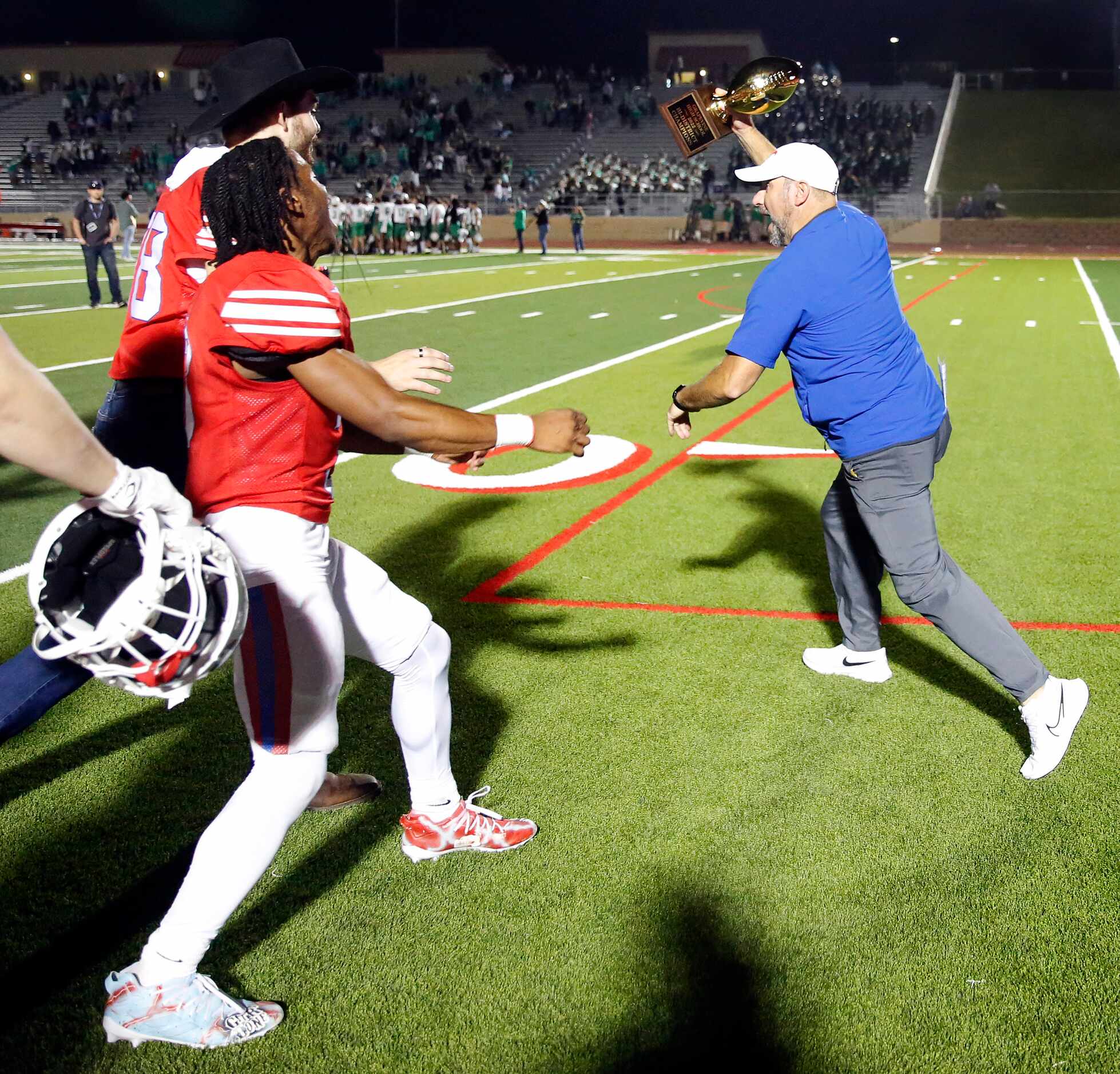 Grapevine head coach Mike Alexander runs away with the 5A bi-district playoff trophy after...