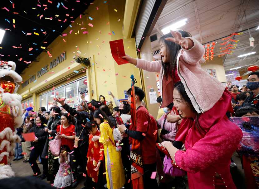 Avery Tran, 4, of Arlington tries to give a red envelope to lion dancers with her mother...
