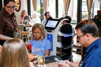 A server removes food from the food delivery robot Panchita at La Duni in Dallas. The young...