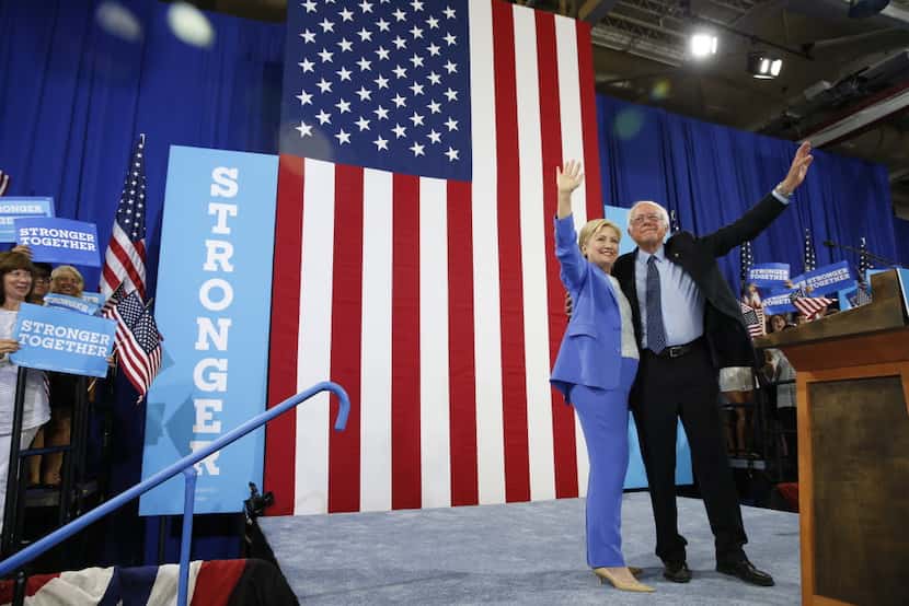 Hillary Clinton and Sen. Bernie Sanders, I-Vt. wave during a rally in Portsmouth, N.H.