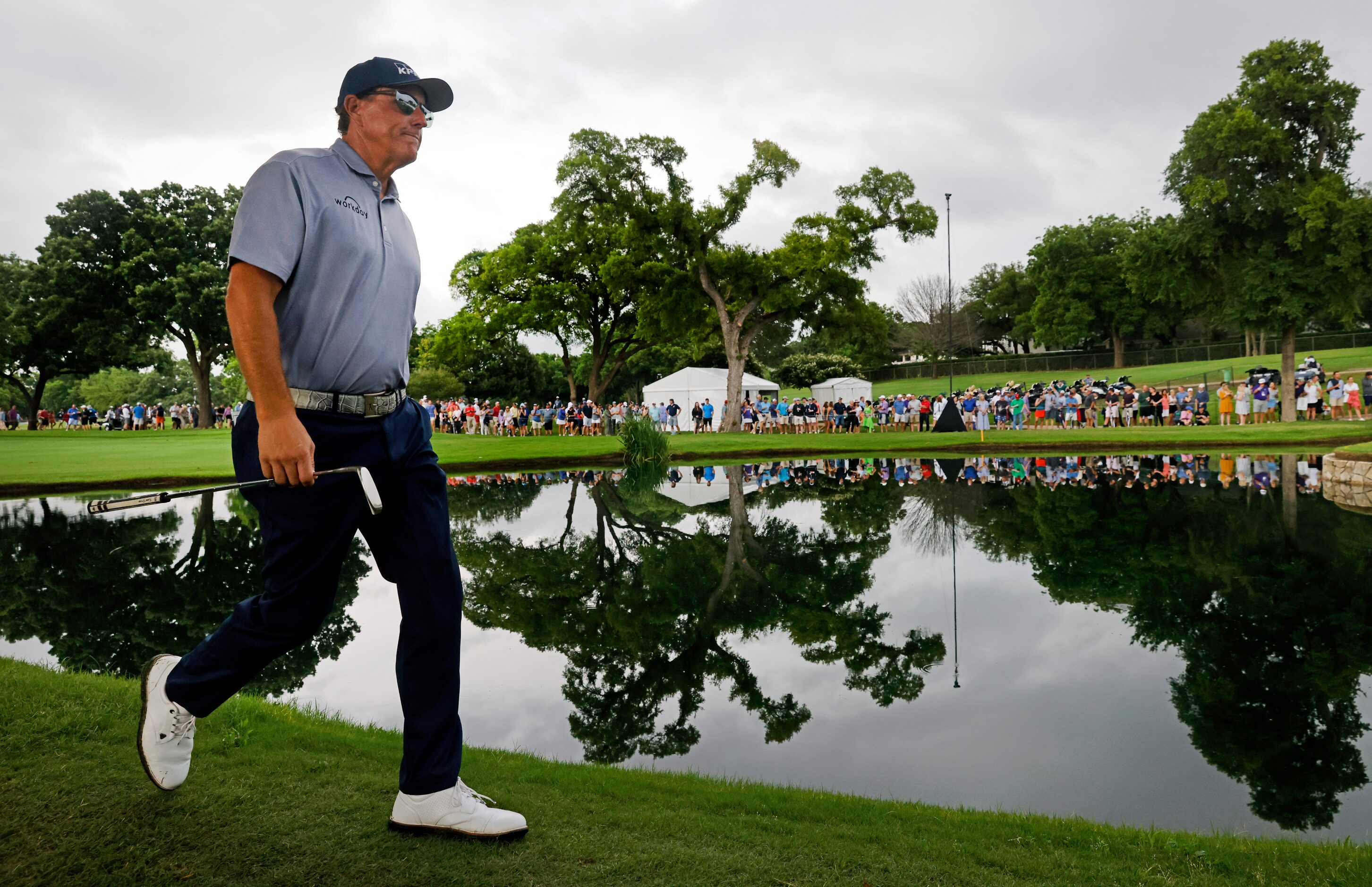 Professional golfer Phil Mickelson passes by the the pond on No. 9 after hitting onto the...