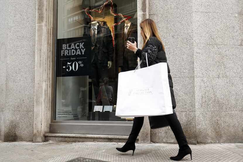 A shopper passes a Black Friday advertisement carrying a Gianni Versace SpA branded shopping...