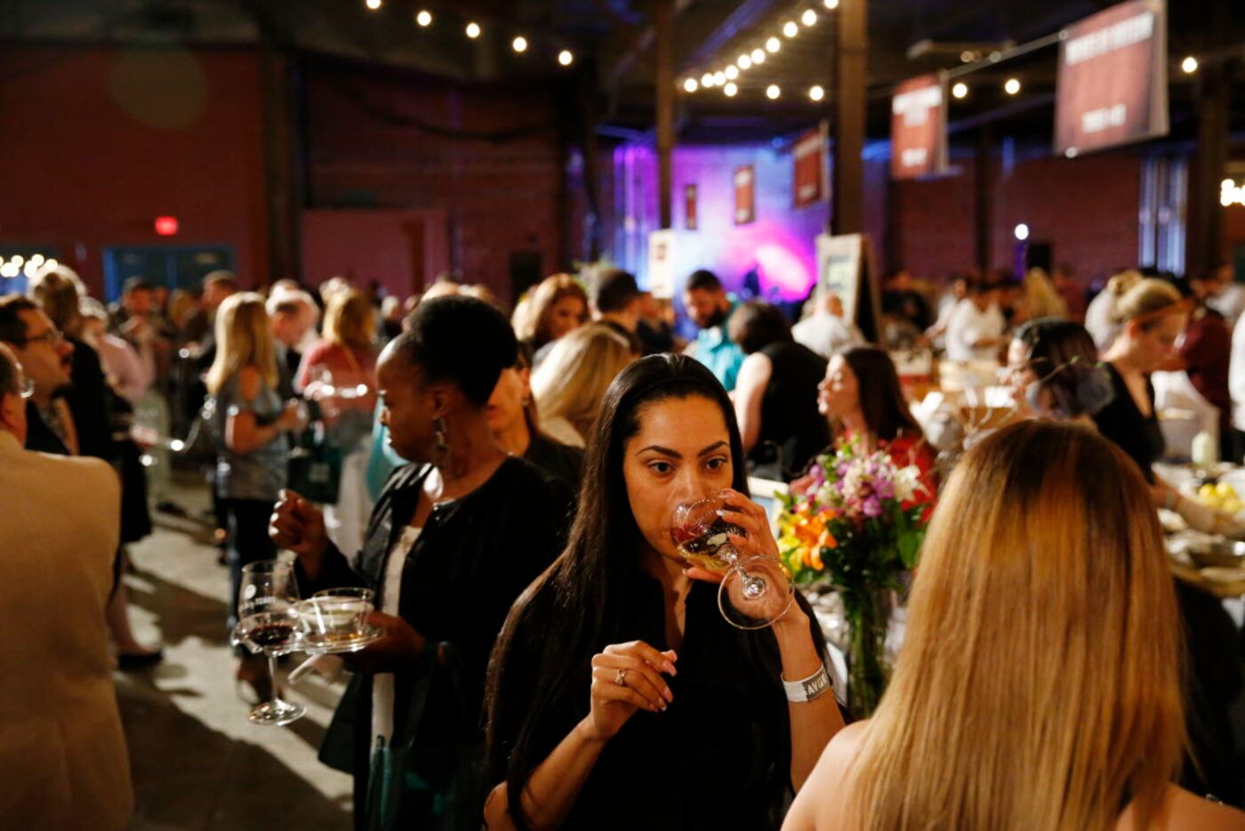 Nena Mendez, of Dallas, tastes wine from R&R Selections during the Grand Tasting event at...