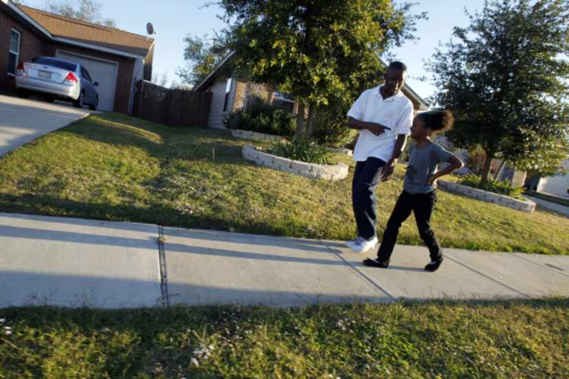 John Thomas Jr., 12, and his sister Camile Thomas, 7, walk through their neighborhood -- one...