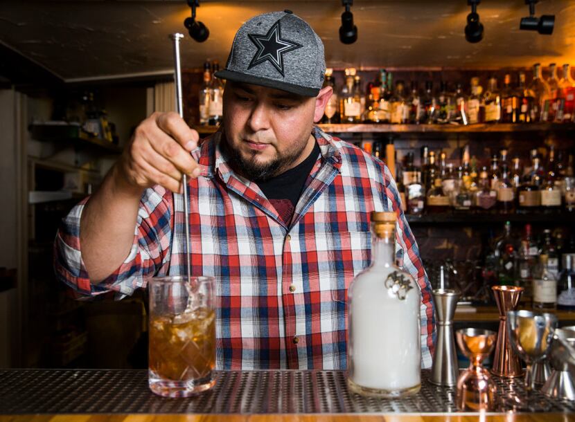 Mixologist Manny Casas mixes cocktail ingredients together in a mixing pitcher.