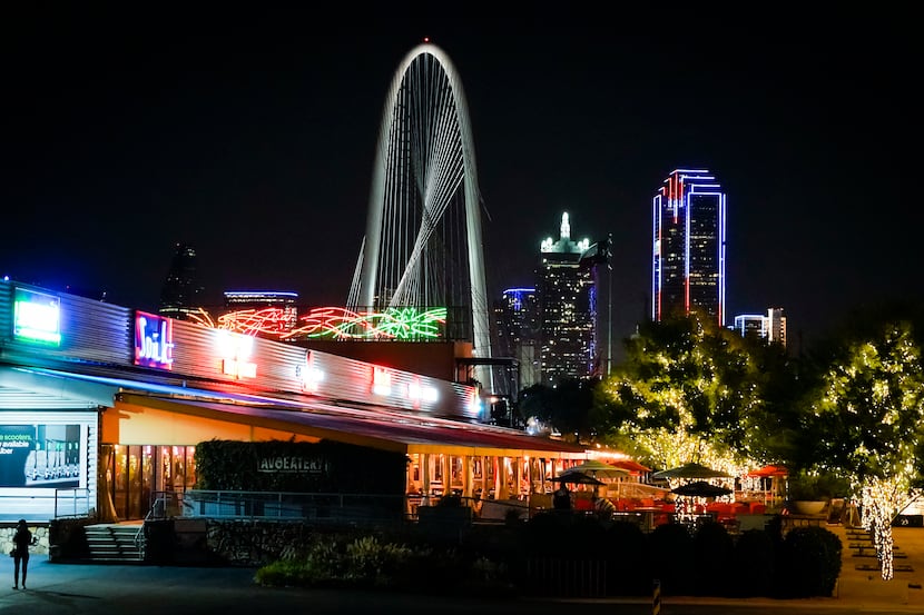 Exterior view Trinity Groves with downtown and the Margaret Hunt Hill Bridge seen at night...