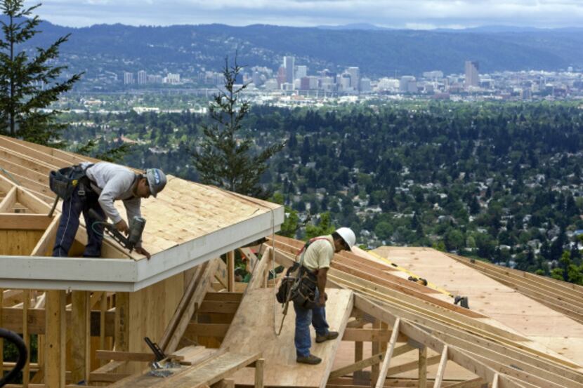 With downtown Portland in the background, workers frame homes atop Mount Scott. The area...
