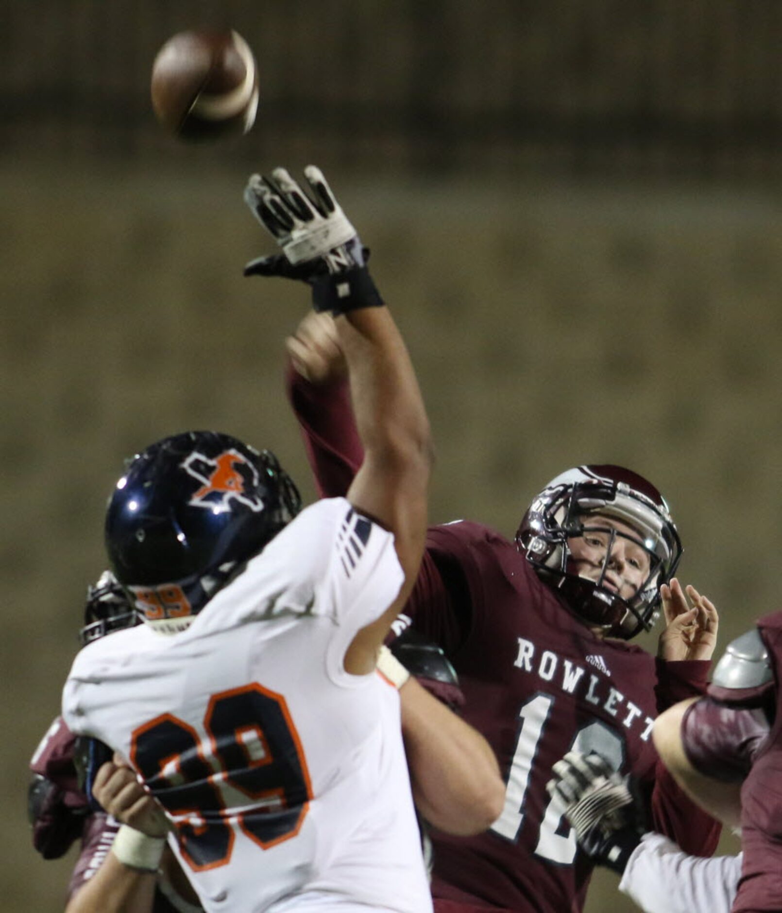 Rowlett quarterback Logan Bonner (12) launches a long pass downfield despite the pressure...