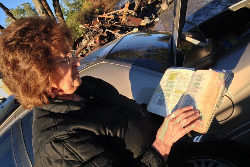 Ingrid Acosta holds one of two Bibles spared by a fire at her home in Irving.