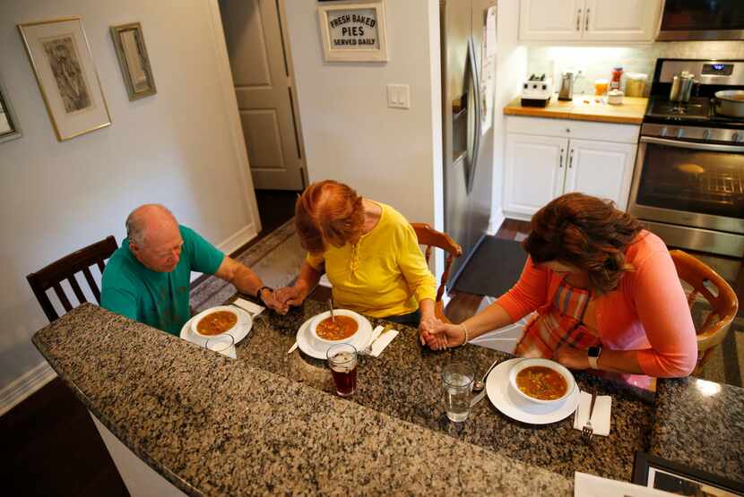 Henry Brigman, Iris Brigman and Amy Hardesty pray before dinner at the Brigman home in...