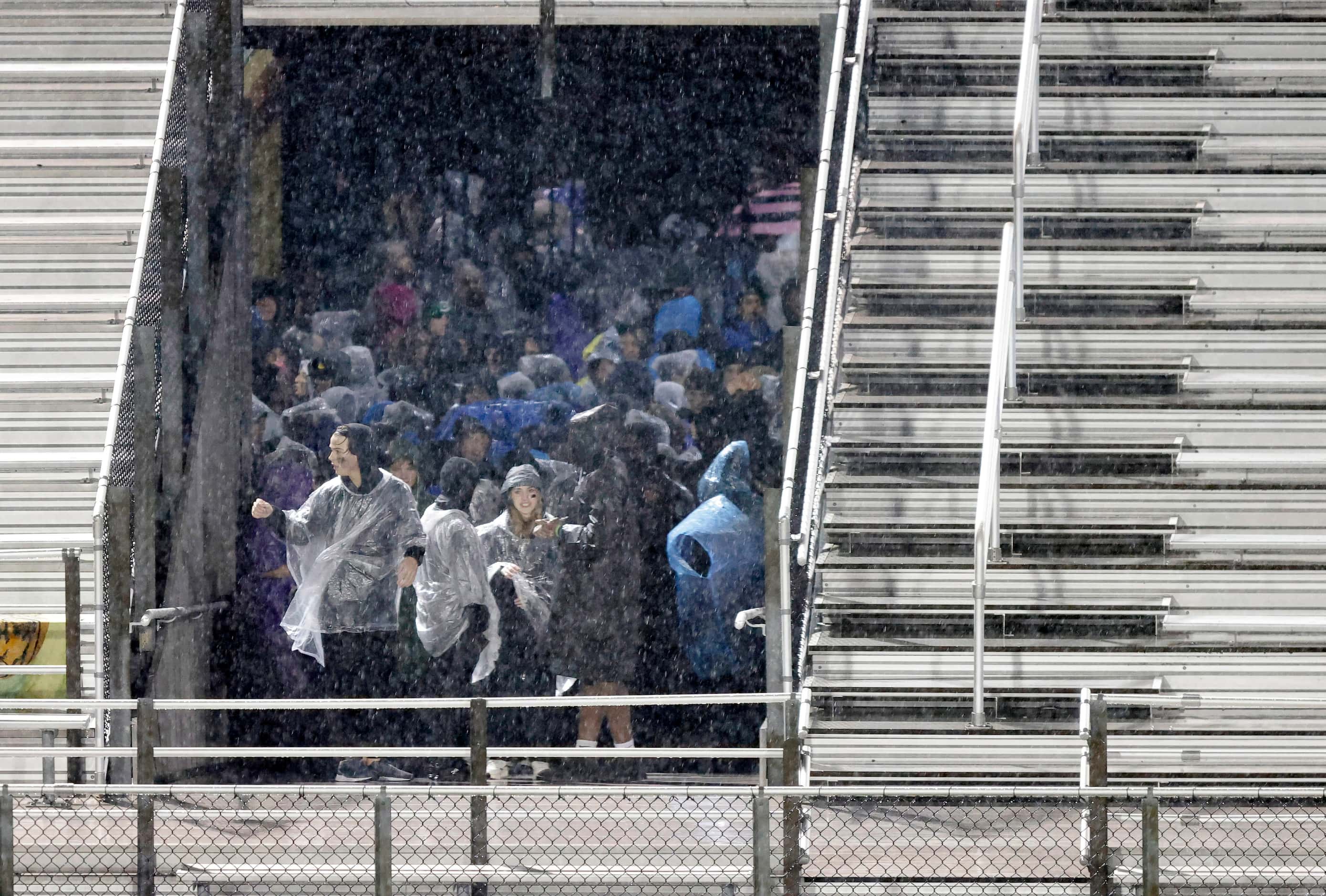 Byron Nelson fans take cover under the stands of Dragon Stadium because of a lighting delay...