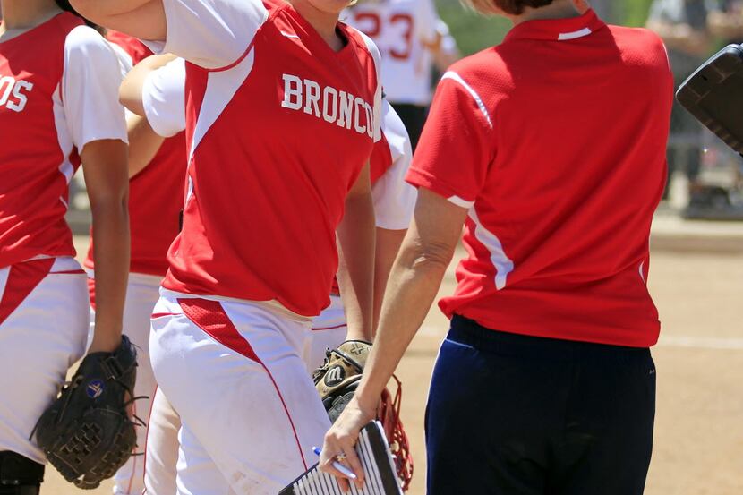 McKinney Boyd starting pitchier Erin Riding (6) slaps hands with coach Mo Fritz, right, as...