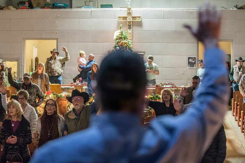 Congregation members raise their hands during a service at Coke County Cowboy Church.