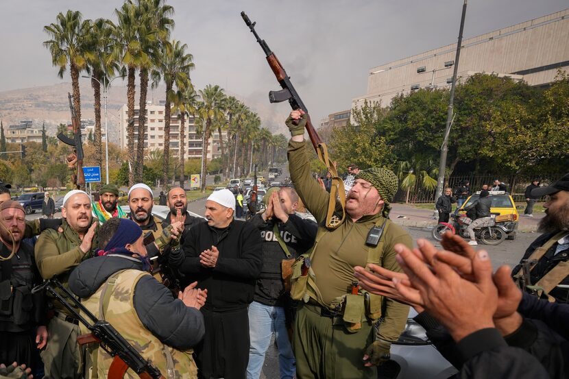 Opposition fighters celebrate the take over of the city by the insurgents in Damascus,...