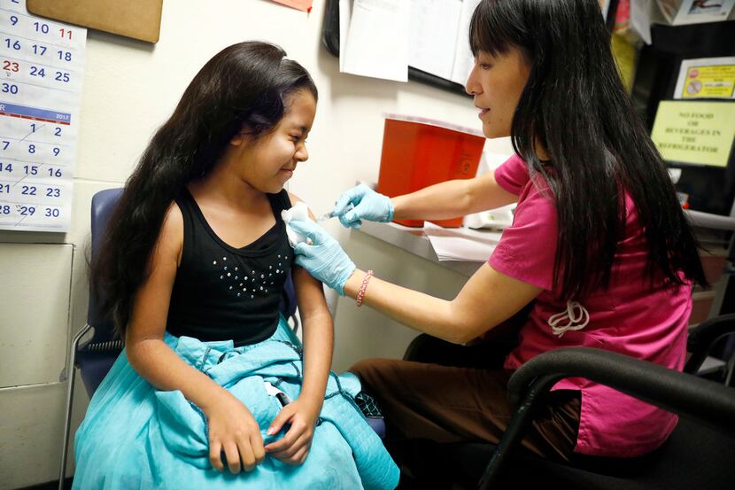 Hailey Esquivel, 8, winces as she receives an influenza shot from nurse Jenny Wang at the...