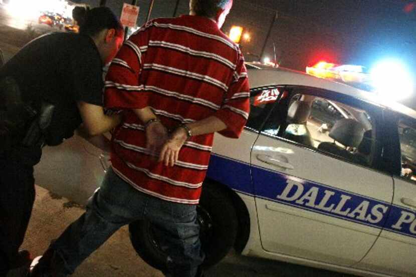 Una agente de policía de Dallas revisa a un menor de edad que violó el toque de...
