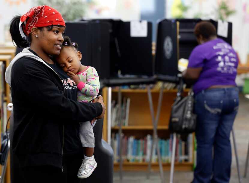 Crystal Coleman (left) holds her daughter, Christani Turner, while waiting to vote Tuesday...