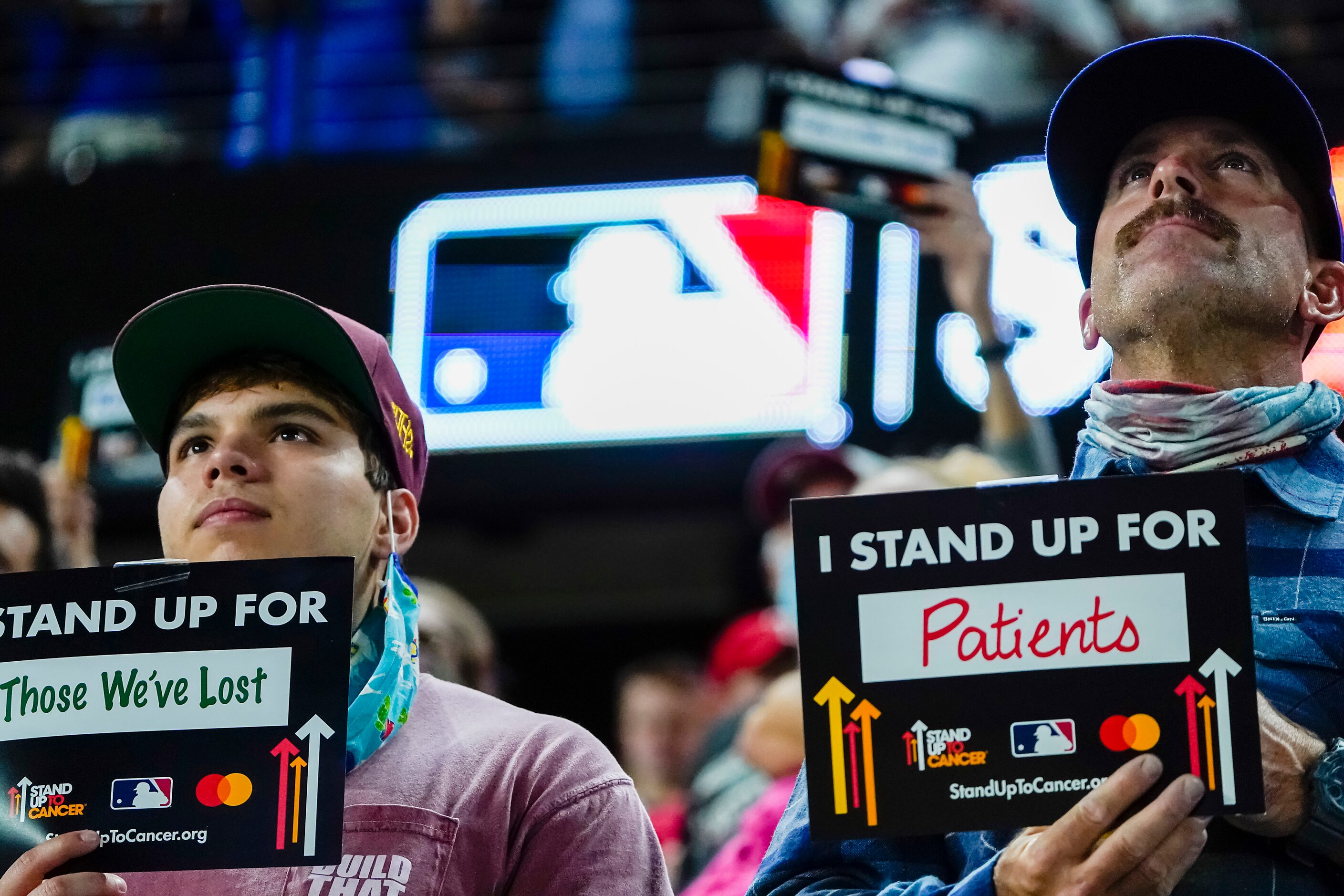 Fans hold up signs as part of the Stand Up To Cancer campaign during the fifth inning in...